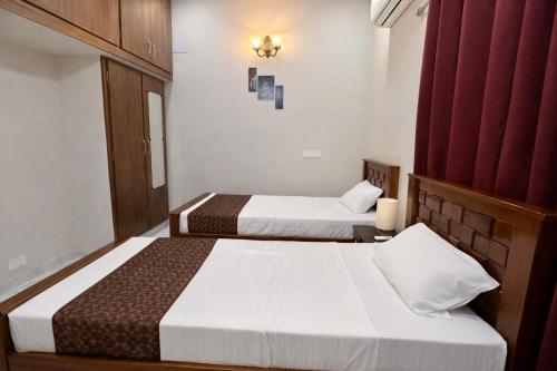 two beds in a hotel room with red curtains at Sri Apartment Homestay 2BHK Pondicherry A2 in Pondicherry