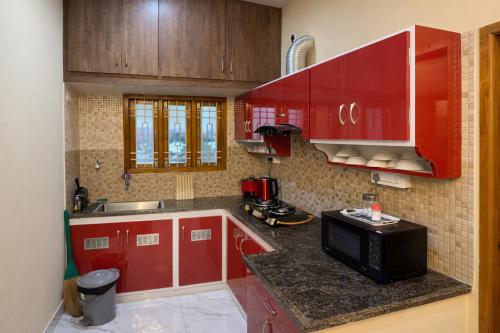 a small kitchen with red cabinets and a microwave at Sri Apartment Homestay 2BHK Pondicherry A2 in Pondicherry