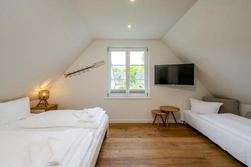 a attic room with two beds and a television at Traumgarten Villa Harmonie in Prerow