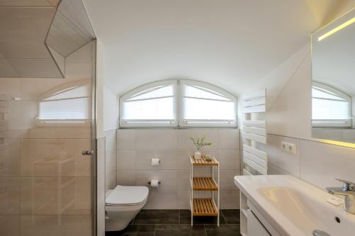 a white bathroom with a toilet and a sink at Traumgarten Villa Harmonie in Prerow