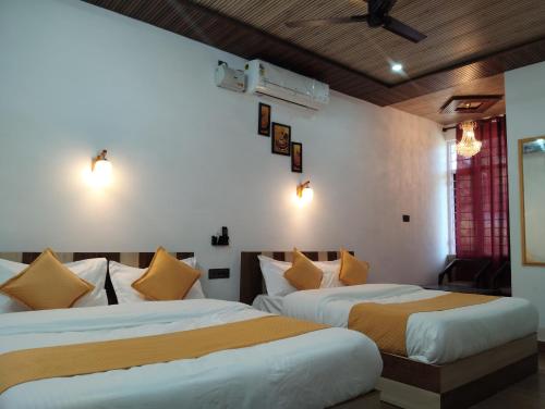 two beds in a room with white and yellow pillows at Hotel Aqua Waterfall in Dharamshala