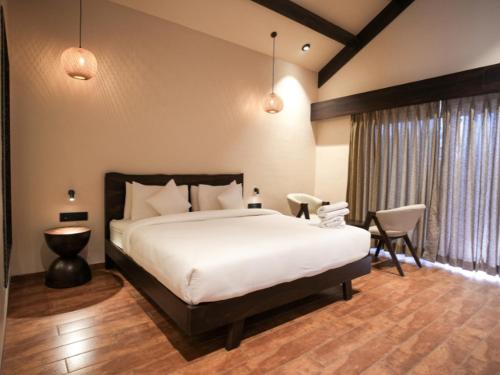 a bedroom with a bed and chairs and a window at Velora The Luxury Resort in Māndu