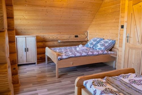 a bedroom with two beds in a log cabin at Bali domy RESORT & SPA in Laskowa