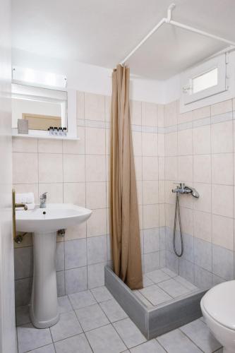 a bathroom with a shower and a sink and a toilet at White island rooms in Panteli