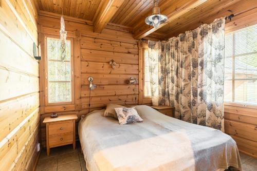 a bedroom with a bed in a wooden cabin at Koivulankaari 17 in Tahkovuori