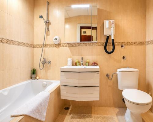 a bathroom with a tub and a toilet and a sink at Hotel Orbita in Varna City