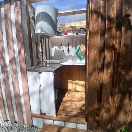 a kitchen with a sink in a wooden wall at Miami Jungle Glamping Experience in Korjuse