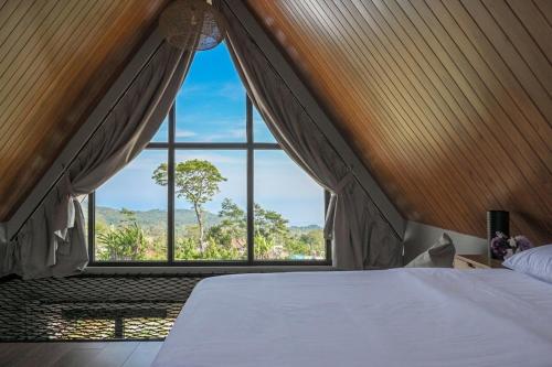 a bedroom with a bed and a large window at Le Nid du Clair de Lune in Gitgit