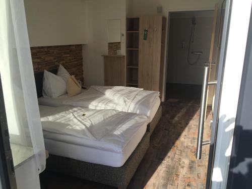 a bed with white sheets and pillows in a room at Burg Rooms - 24h Self-Check-in in Spielberg