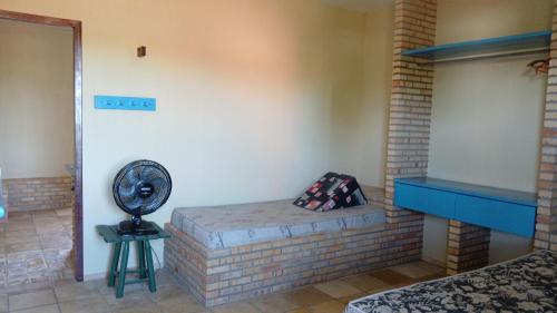 a room with a brick fireplace and a fan at Flat Casa Taiba 2001 in Taíba