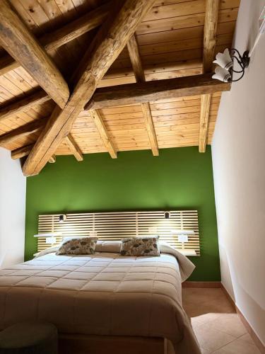 a green bedroom with a bed with a wooden ceiling at Il noceto dell'Etna in Giarre