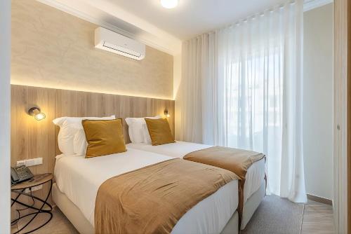 a bedroom with a large white bed with yellow pillows at Vila Baleira Residence in Funchal