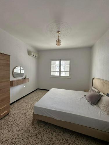 a white bedroom with a bed and a window at villa Flamingo in Sousse