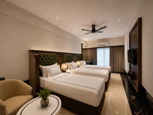 a hotel room with two beds and a ceiling fan at Hotel Mulki International in Mūlki