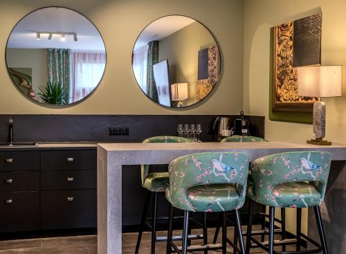 a bathroom with two mirrors and a counter with stools at Platán Villa - Platán Tata in Tata