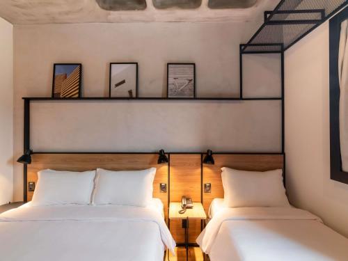 two beds in a room with two lamps and two beds at ibis Tubarão in Tubarão