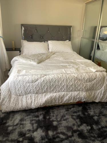a bedroom with a large bed with white sheets and pillows at Elimisam stays in Kitwe