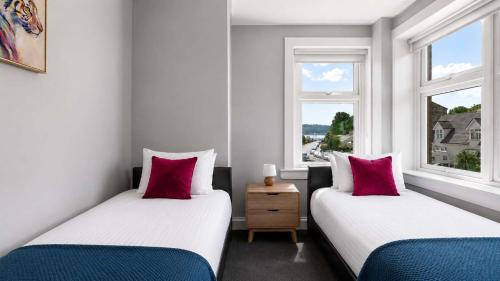 two beds in a room with two windows at Parkview Apartment in Rothesay