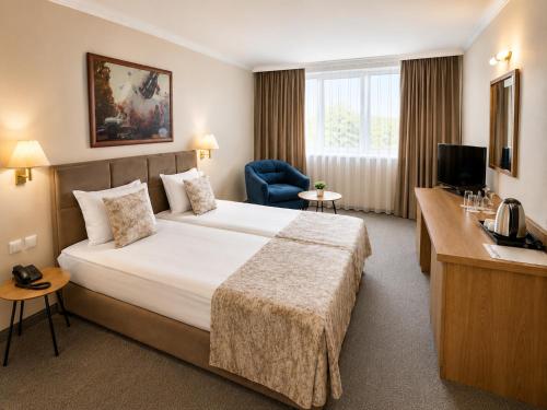 a hotel room with a large bed and a chair at Hotel Orbita in Varna City