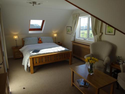 a bedroom with a bed and a chair and a window at Hunters Croft in Sway