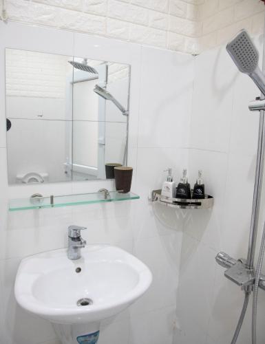 a white bathroom with a sink and a mirror at New Sala Homestay in Hue