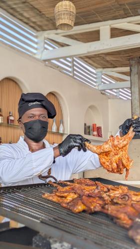 a man in a mask is preparing food on a grill at Hôtel villa blanca in Lomé