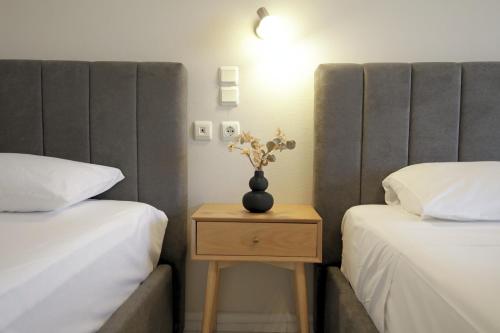 a bedroom with two beds and a table with a vase on it at Mochlos Studios in Mochlos