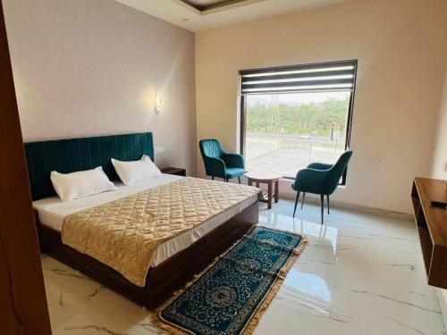 a bedroom with a bed and two chairs and a window at Mount Green Hotel Bharatgarh in Bharatgarh