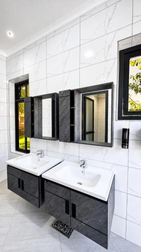 a bathroom with two sinks and two mirrors at Mama Thea homes in Moshi