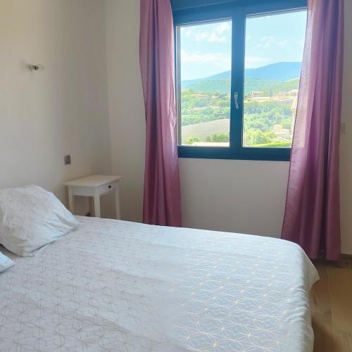a bedroom with a bed and a window with purple curtains at Gite Aubanel' Drôme Provencale in Saint-Auban-sur-Ouvèze