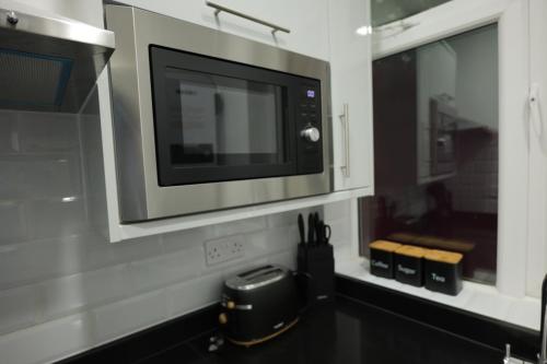 a kitchen with a microwave oven above a counter at Deaf Property - Woolwich Elizabeth Line Studios in Woolwich