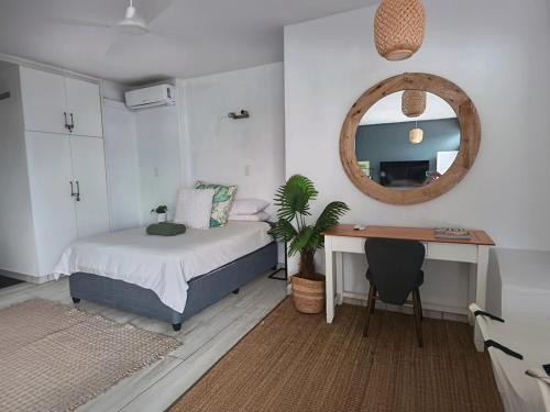 a bedroom with a bed and a desk and a mirror at Umdloti Holiday Resort 208 in Umdloti