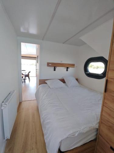 a bedroom with a white bed and a bench on the wall at Bateau Lac du Der - Nuisement - Navigation in Les Petites-Côtes