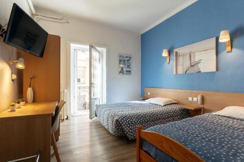 a hotel room with two beds and a television at Hôtel Colisée-Verdun Centre Gare Saint-Roch in Montpellier