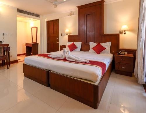 a bedroom with a large bed with red pillows at Padipura Residency in Alleppey