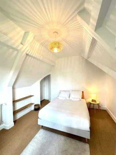 a bedroom with a white bed and a ceiling at La Villa Convivium - Chambres privées in Rouen