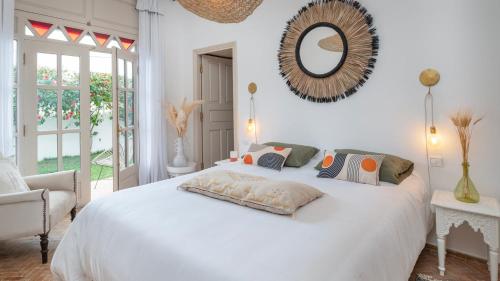 a bedroom with a white bed with a mirror on the wall at Villa NoYa in Oualidia