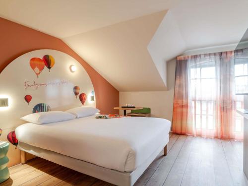 a bedroom with a large white bed with balloons on the wall at ibis Styles Saint-Jean-de-Luz Donibane in Saint-Jean-de-Luz