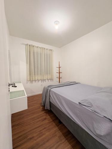 a white bedroom with a bed and a window at Apê aconchegante e climatizado - Villa Kennidy in Caruaru