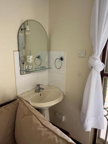 a bathroom with a sink and a mirror and a bed at Happy Fish Villa in Entebbe