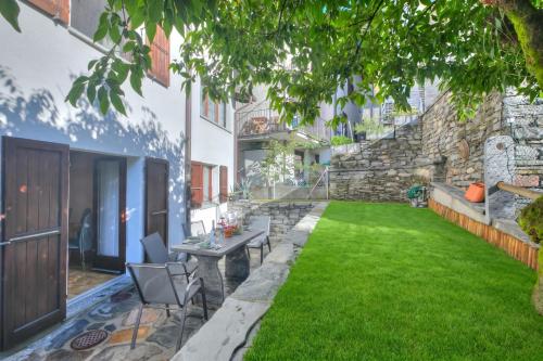 a garden with a table and chairs and a stone wall at Ca Cornocc with Private Terrace in Gordola - Happy Rentals in Gordola