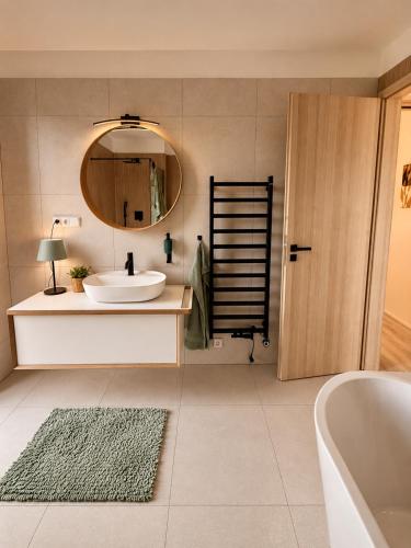 a bathroom with a sink and a mirror and a tub at Modern House with Private Pool & Terrace in Červená Třemešná