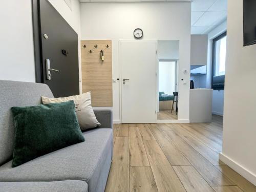 a living room with a couch and a clock on the wall at POPIELATE Apartamenty in Żywiec