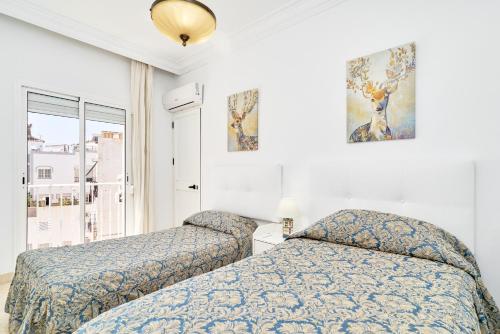 a bedroom with two beds and a window at Dúplex céntrico, 2 grandes terrazas in Nerja