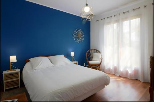 a blue bedroom with a white bed and a blue wall at Les Anthémis in Gujan-Mestras