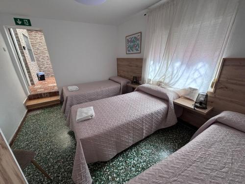 a room with three beds and a desk and a window at Hostal Gutierrez in Ceuta