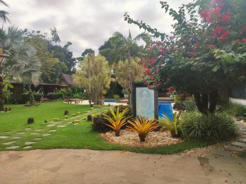 a garden with flowers and a sign in the grass at Villa Cozy - Pousada Boutique in Arraial d'Ajuda