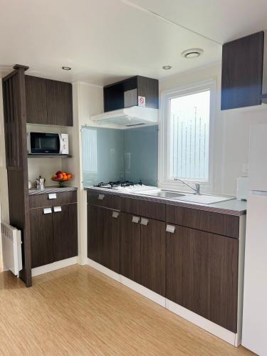 a kitchen with brown cabinets and a sink and a window at Camping benquerencia in Pena