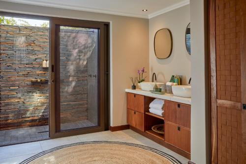 a bathroom with two sinks and a sliding glass door at Taj Bush Lodge in Hoedspruit