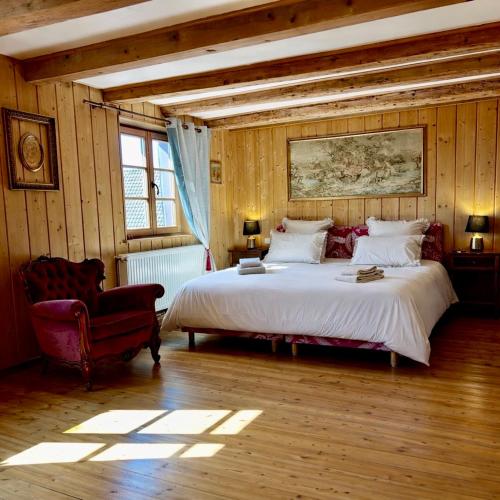 a bedroom with a large bed and a chair at L'Héritage 1779 in Duntzenheim